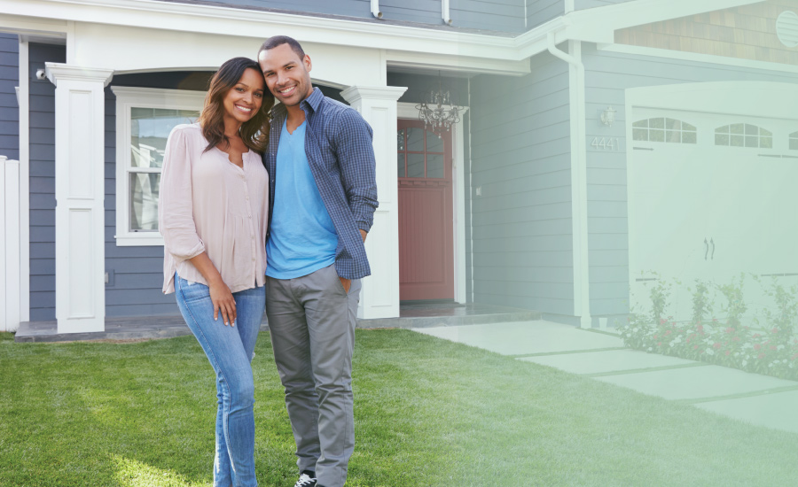 Young couple smiling in front of their newly purchased home